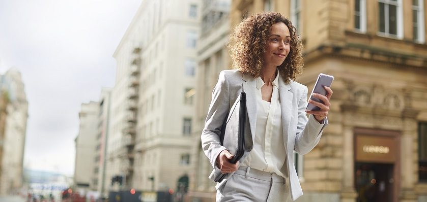 Business woman walking through city smiling