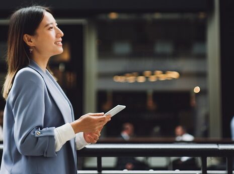 A businesswoman on a city street holding a mobile phone,