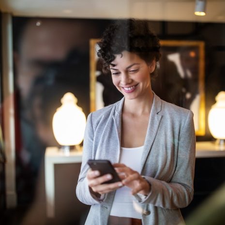 A businesswoman smiling as she types on her phone.