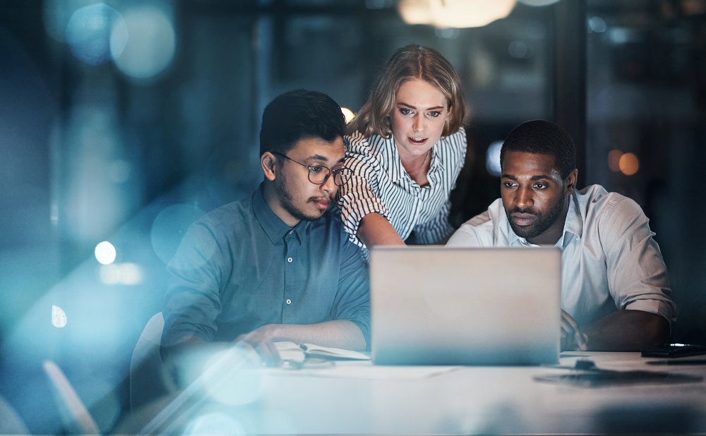 Three IT colleagues working together around a computer.