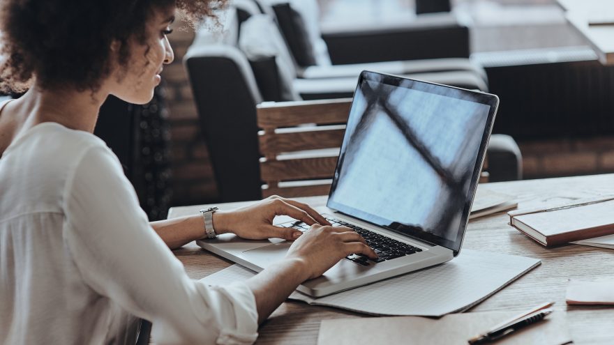 A young personal assistant working on a laptop and notepad.