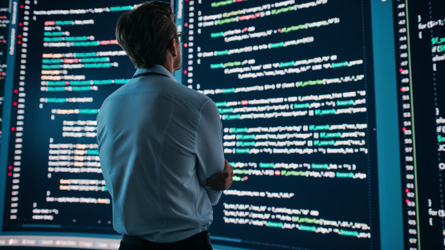 Man looking at screen with code on.