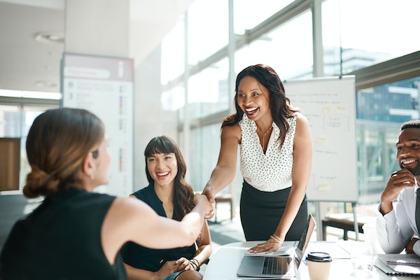 smartly dressed women in an office shaking hands
